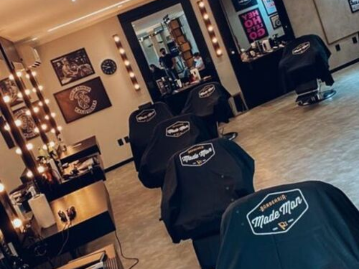 Ambiente interno da Barbearia Made Man com cadeiras e espelhos iluminados